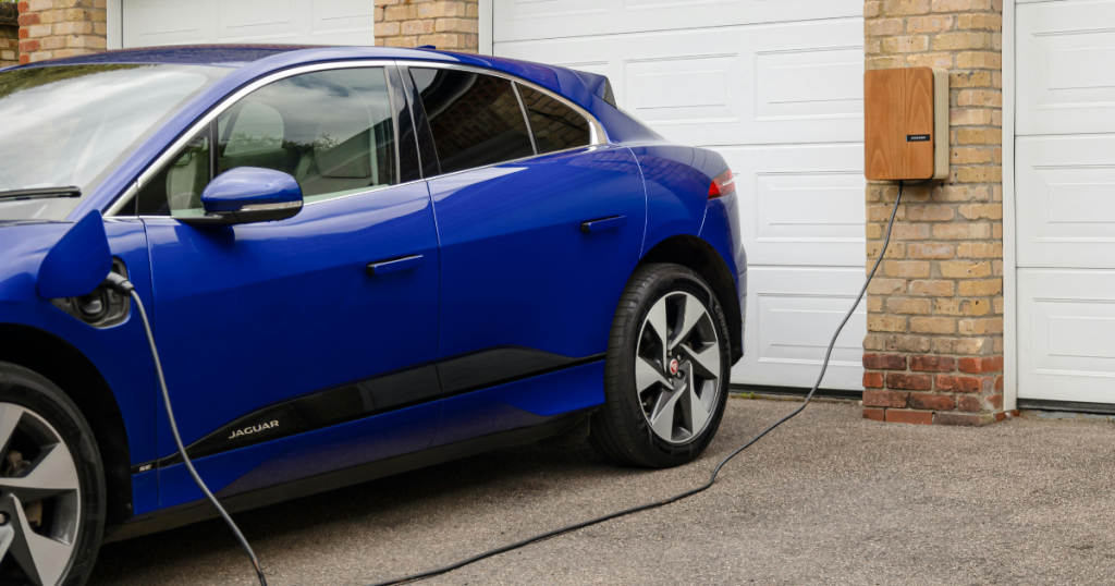 Blue electric vehicle charging in residential driveway at home