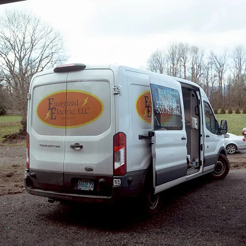 Energized Electric LLC commercial service van parked at a residential job site with its side doors open, ready for electrical work.