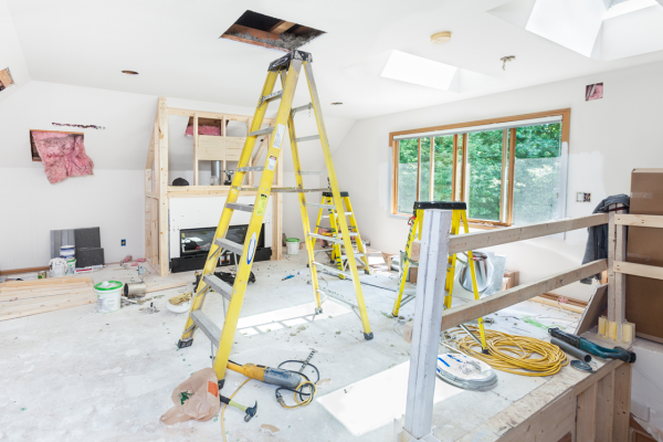 Electrical remodeling of a living room under renovation with step ladder leading to the attic.